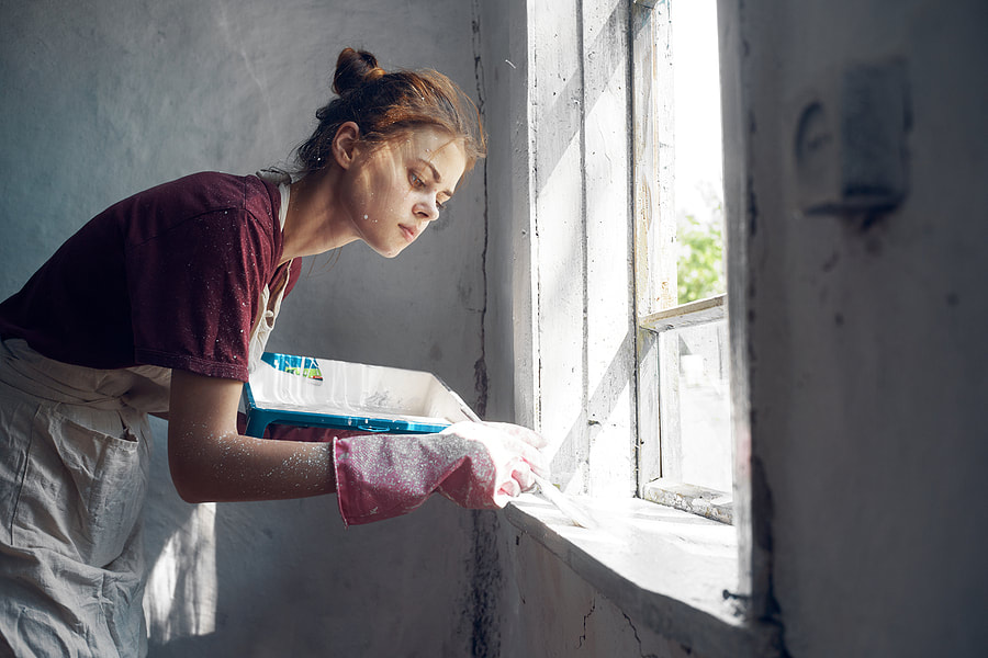 A woman uses a brush to decorate an interior window during renovations in Norwalk, Connecticut.